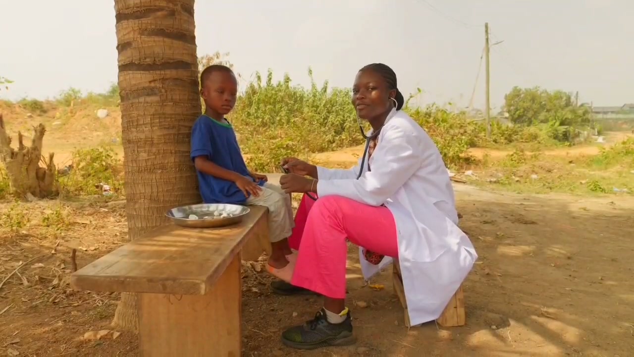 Nigerian clinician caring for a child outdoors